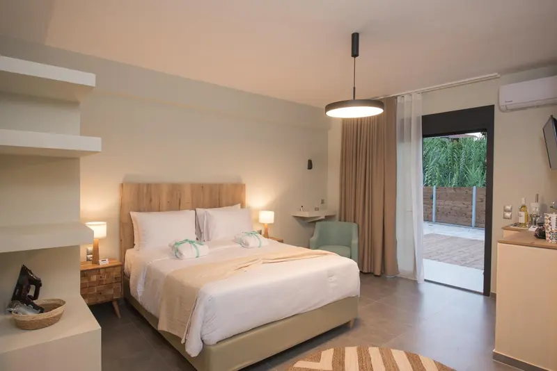 Chambre lumineuse avec un grand lit et un accès à une terrasse.
