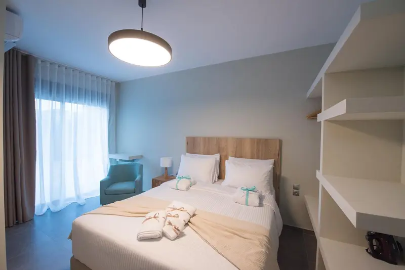 Une chambre lumineuse avec un grand lit et un fauteuil.