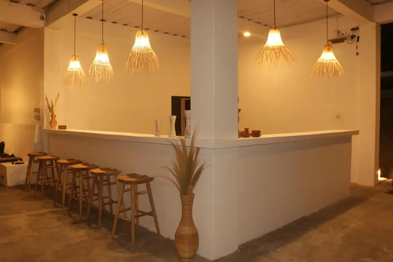 Un comptoir de bar en bois éclairé par des suspensions en fibres naturelles.