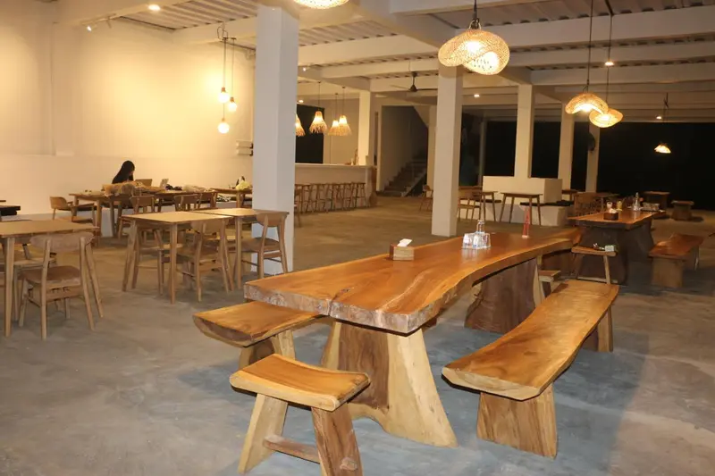Une salle à manger lumineuse avec des tables en bois et des luminaires suspendus.