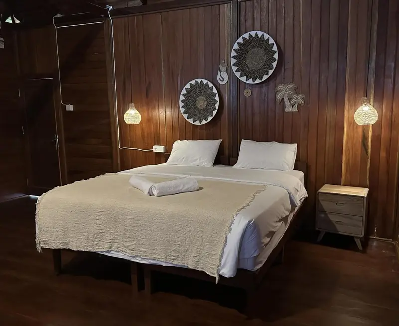 Une chambre avec un grand lit recouvert d'une courtepointe claire et de coussins blancs.