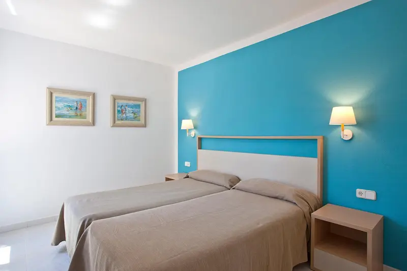 Une chambre lumineuse avec un lit double et un mur bleu.