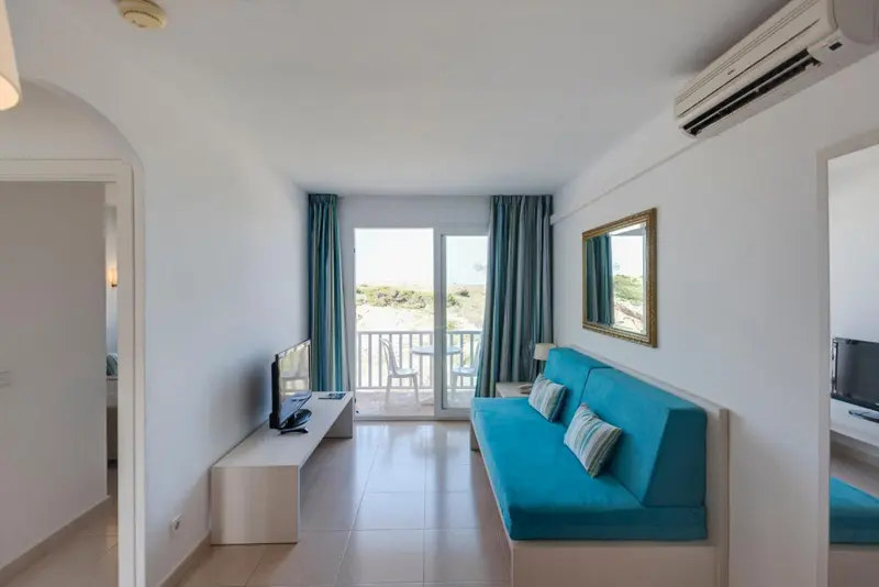 Espace de séjour lumineux avec canapé turquoise et vue sur la mer.