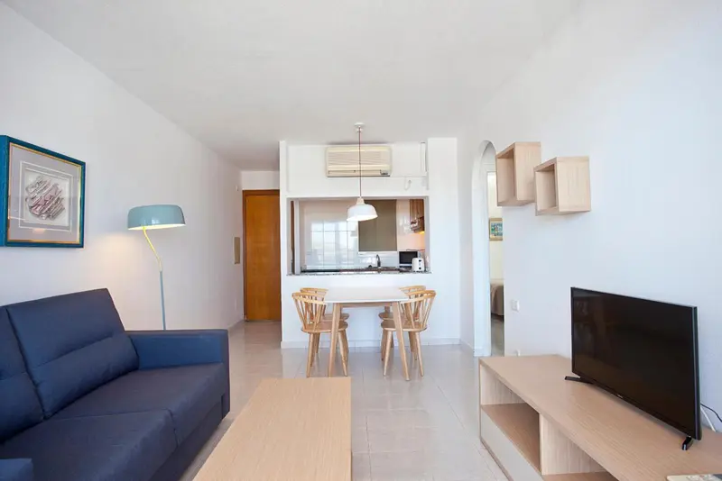 Espace de vie lumineux avec canapé bleu et coin repas en bois clair.