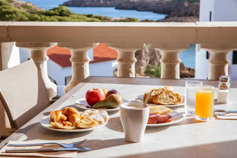Une table est dressée avec un petit-déjeuner face à la mer.