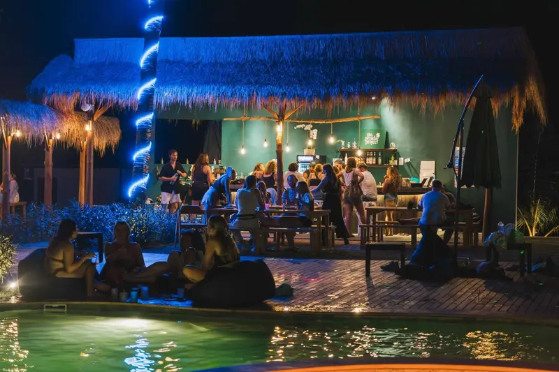 Une terrasse lumineuse avec un bar et des clients assis autour de tables.