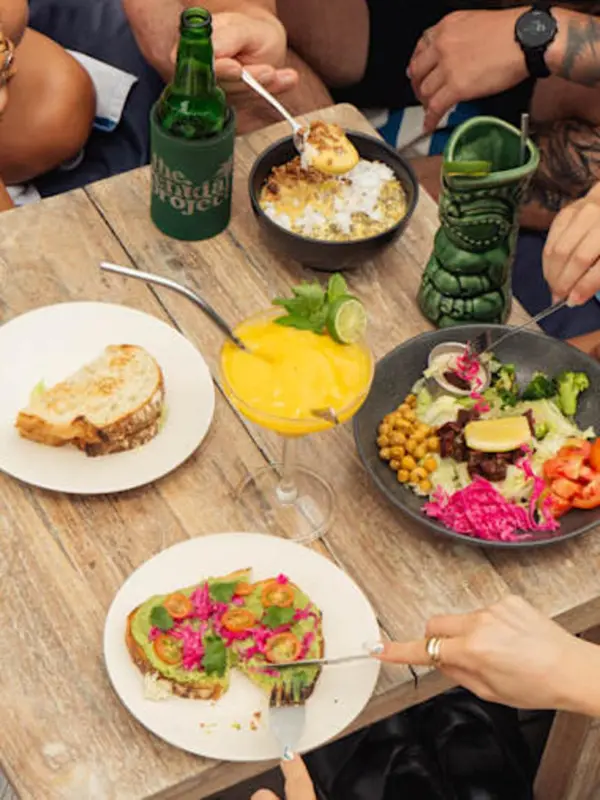 Une table en bois présente une variété de plats colorés et de boissons fraîches.