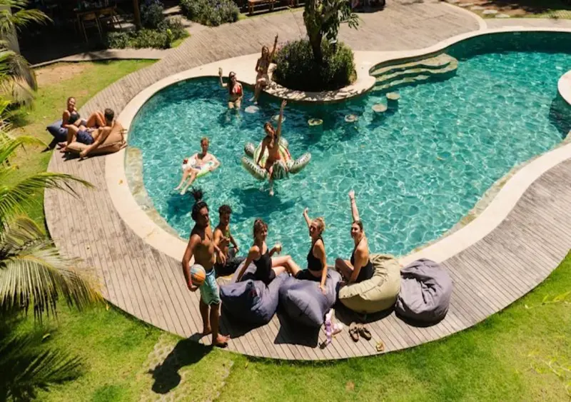 Des personnes se détendent au bord d'une piscine en forme d'haricot.