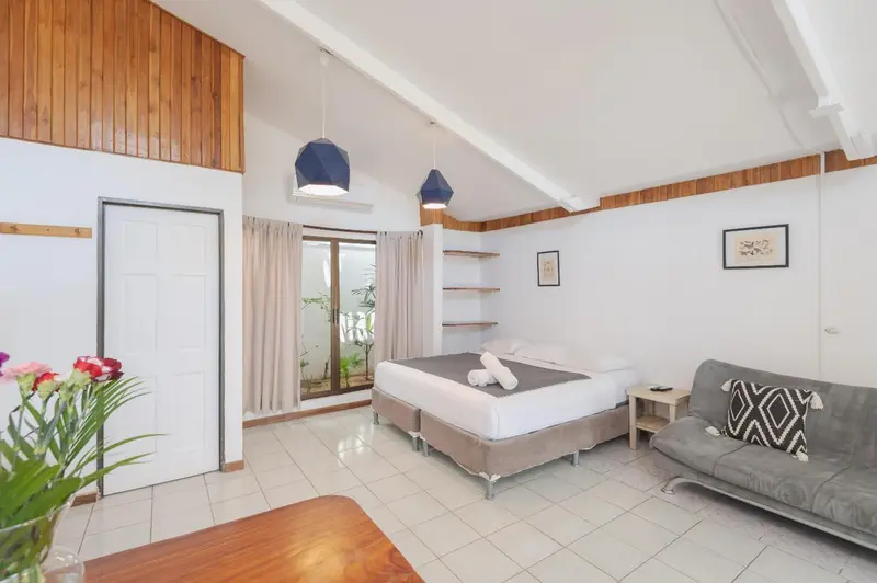 Une chambre lumineuse avec un grand lit et un coin salon.