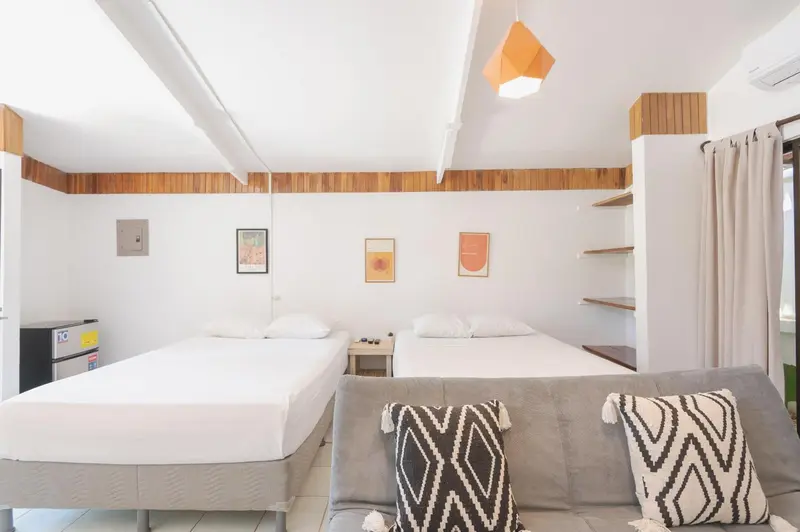 Chambre lumineuse avec deux lits simples et un canapé.