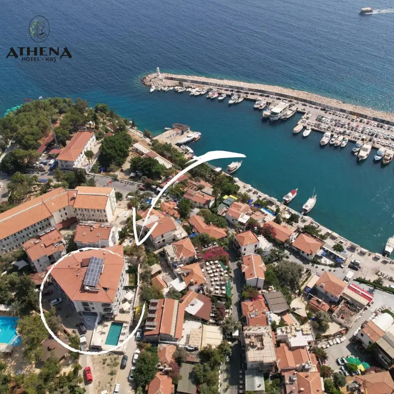 Vue aérienne d'un complexe hôtelier au bord de la mer avec des bâtiments aux toits rouges et une marina.