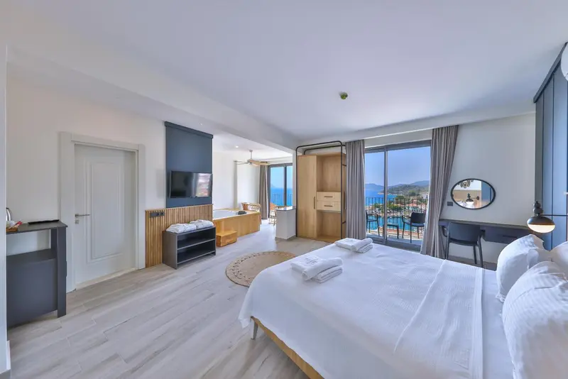 Chambre lumineuse avec un grand lit et une vue sur la mer.