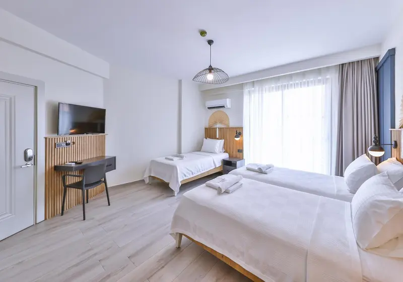 Une chambre lumineuse avec deux lits simples et un bureau.