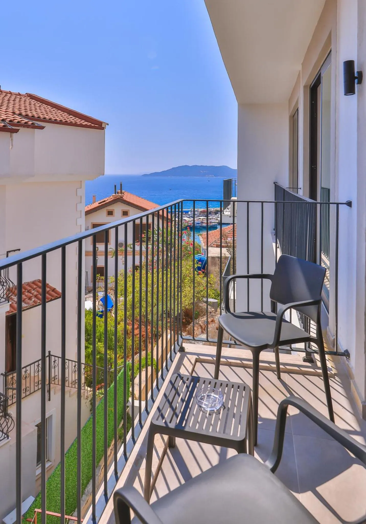 Une terrasse avec mobilier d'extérieur offre une vue sur la mer et les toits.
