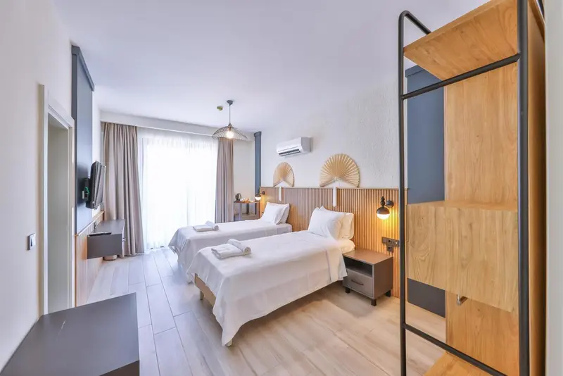 Une chambre lumineuse avec deux lits simples et un mobilier en bois.