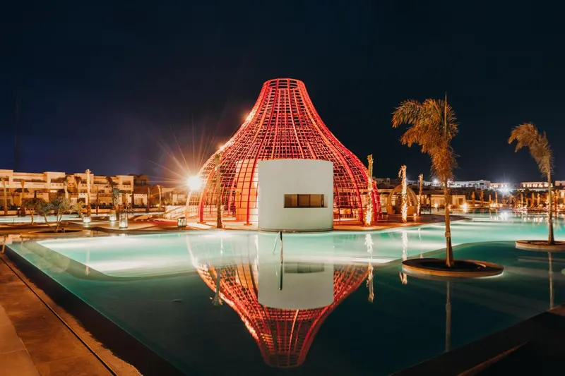 Structure lumineuse au bord d'une piscine la nuit.