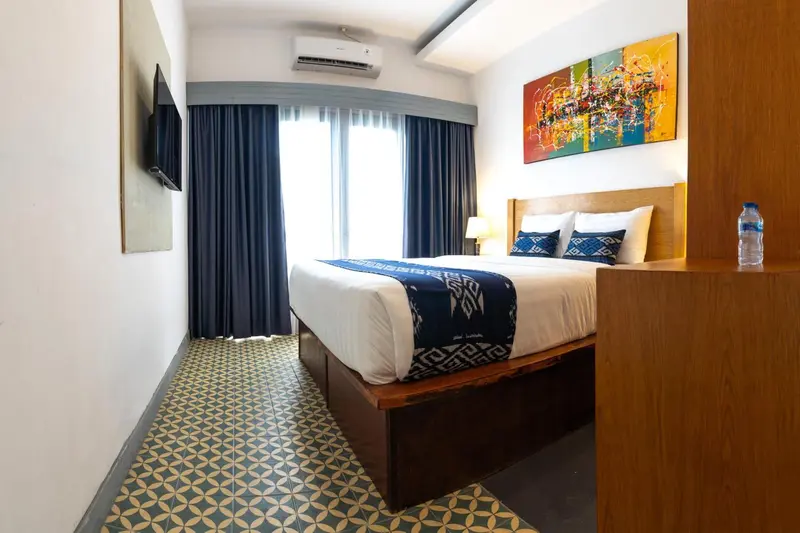 Une chambre lumineuse avec un grand lit recouvert d'une courtepointe décorative.