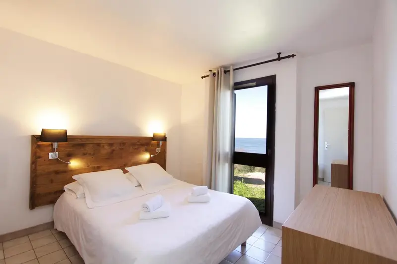Une chambre lumineuse avec un grand lit et vue sur la mer.