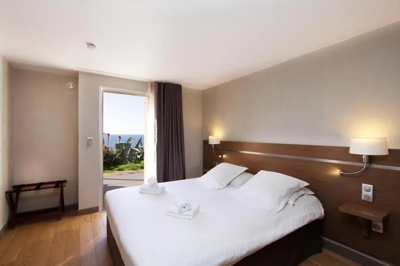 Une chambre lumineuse avec un lit double et un accès à une terrasse.