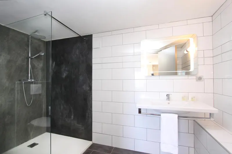 Une salle de bain moderne avec douche à l'italienne et vasque blanche.