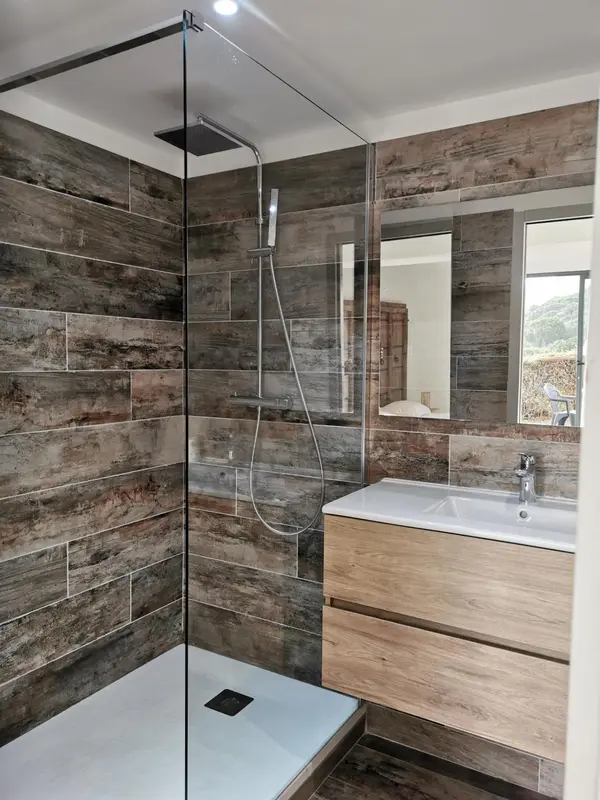 Une douche à l'italienne moderne avec des carreaux de céramique et un meuble vasque en bois.