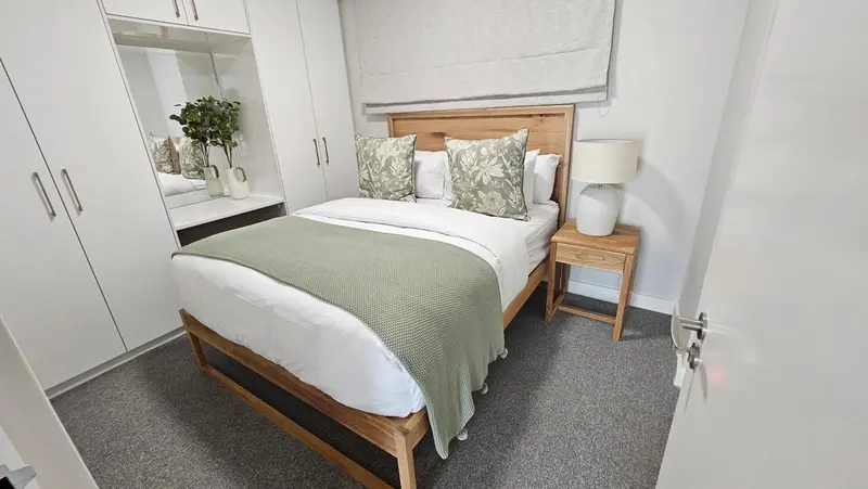 Une chambre lumineuse avec un grand lit et des rangements.