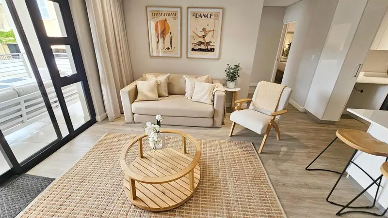 Un salon lumineux avec un canapé beige et des fauteuils en bois.