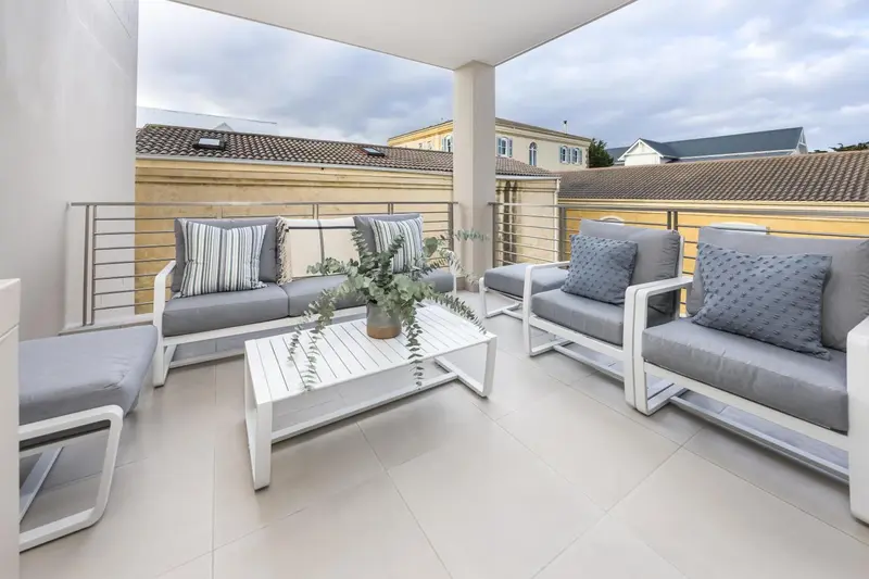 Salon d'extérieur avec canapés et table basse sur une terrasse carrelée.