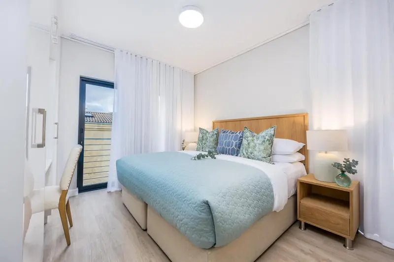 Une chambre lumineuse avec un grand lit et une porte-fenêtre.