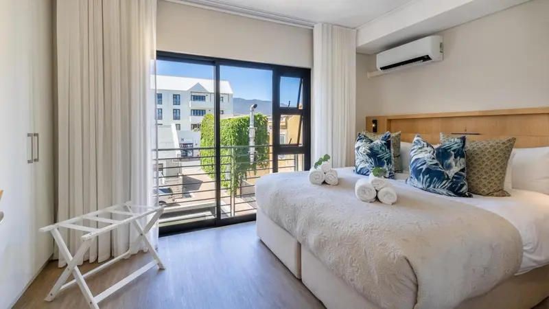 Une chambre lumineuse avec un grand lit et un accès à un balcon.