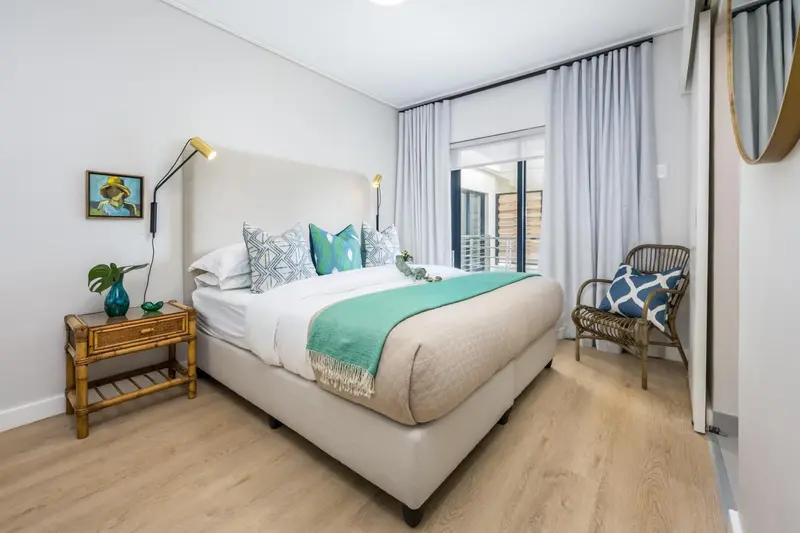 Une chambre lumineuse avec un grand lit et un fauteuil.
