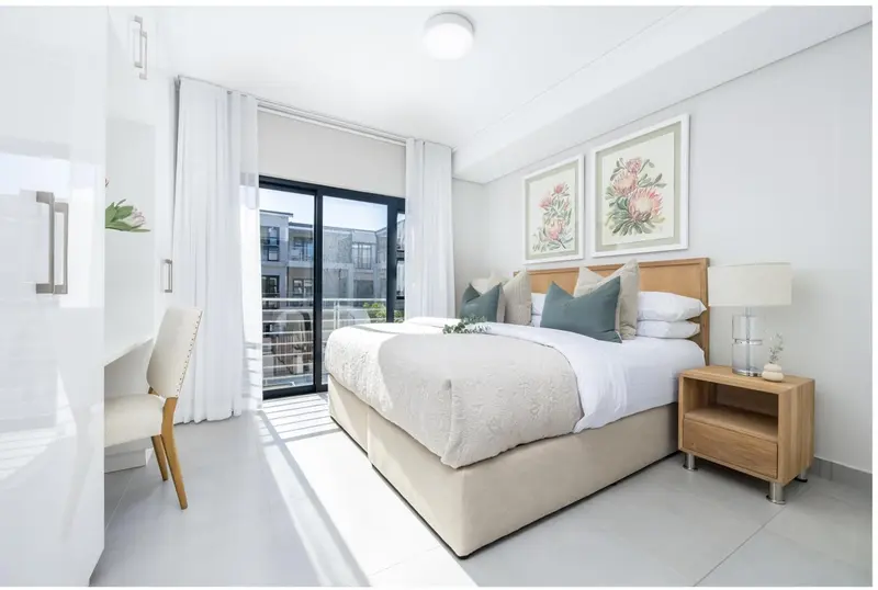 Chambre lumineuse avec un grand lit et un bureau.