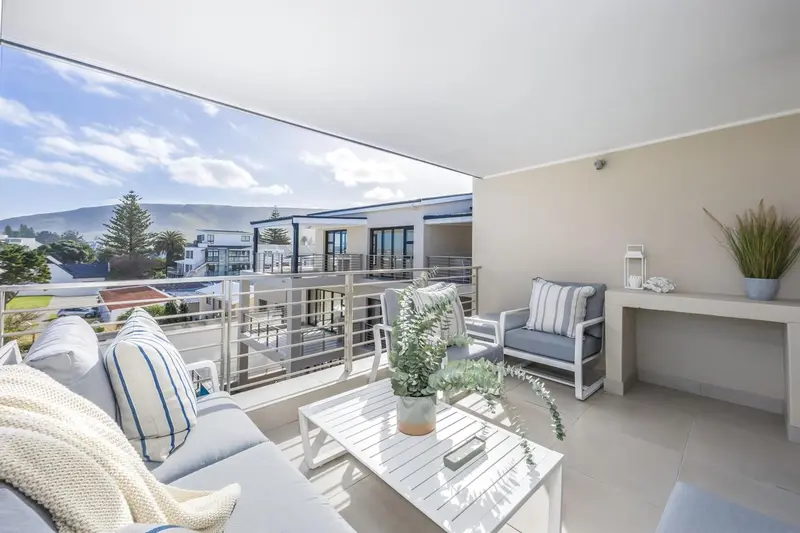 Terrasse aménagée avec canapés et table basse offrant une vue sur la ville.