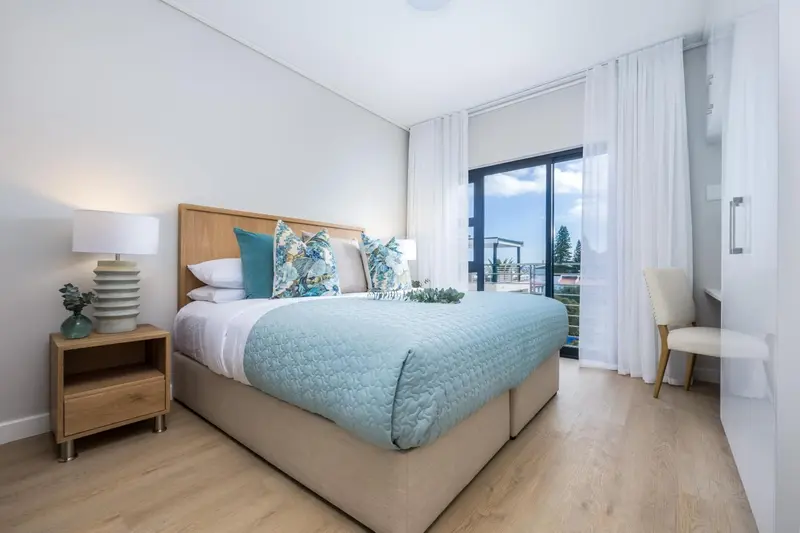 Une chambre lumineuse avec un grand lit et un fauteuil.