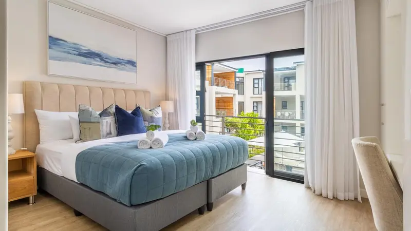 Une chambre lumineuse avec un grand lit et un accès à un balcon.