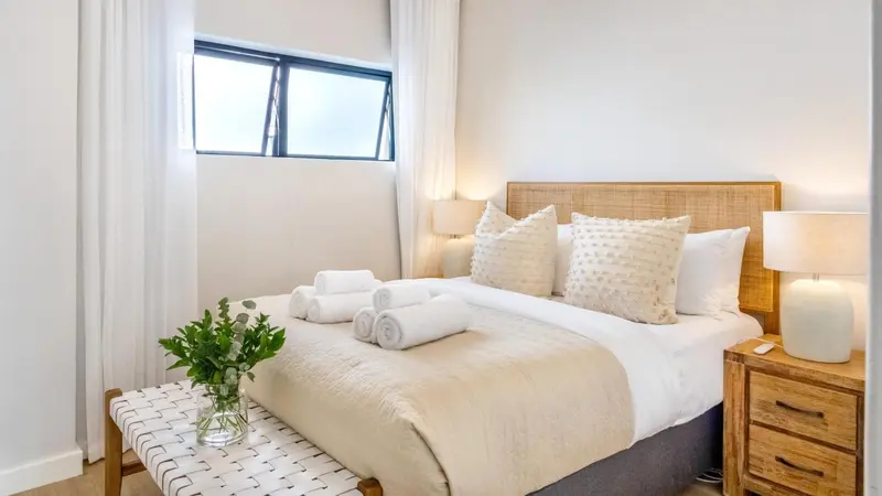 Une chambre lumineuse avec un grand lit recouvert d'une courtepointe et de coussins.