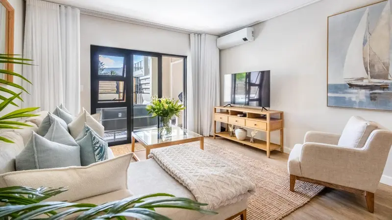 Un salon clair avec un canapé, une table basse et un accès à une terrasse.