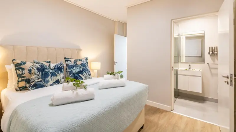 Une chambre lumineuse avec un grand lit décoré de coussins bleus et blancs.