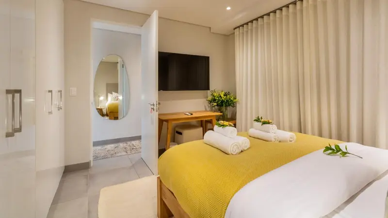 Une chambre lumineuse avec un lit jaune et un bureau en bois.