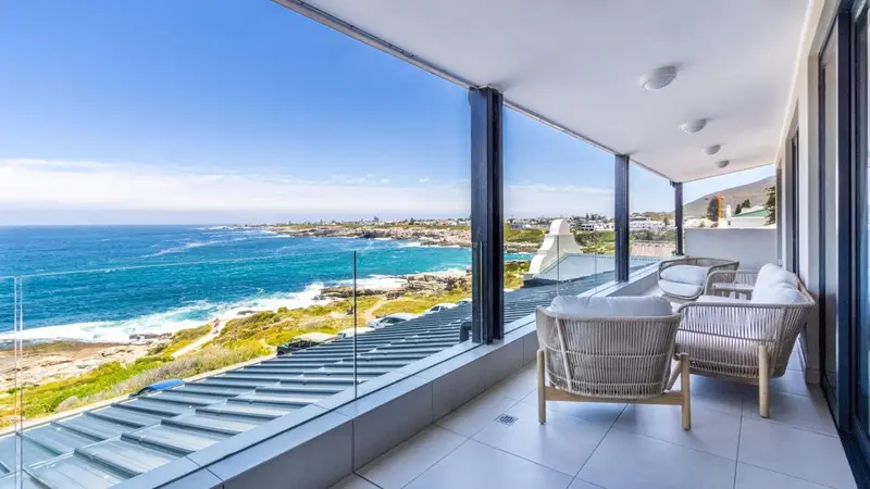 Terrasse moderne avec mobilier d'extérieur donnant sur une côte rocheuse et la mer.