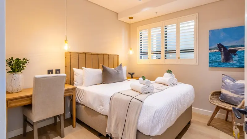 Une chambre lumineuse avec un lit double et un bureau.