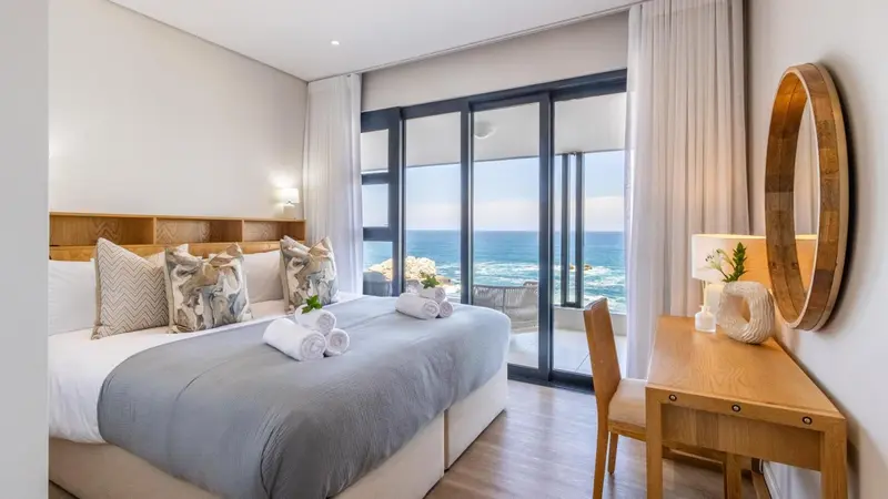 Chambre lumineuse avec un grand lit et vue sur la mer.