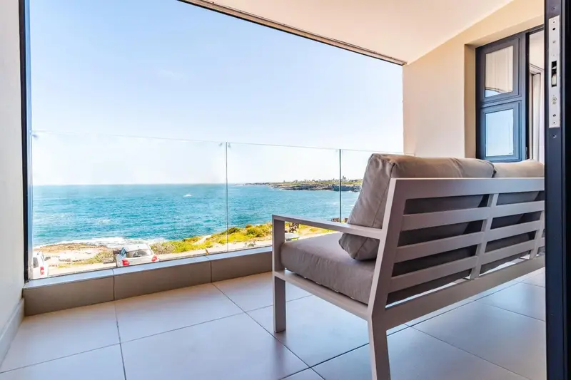 Vue sur la mer depuis une terrasse aménagée avec un canapé.