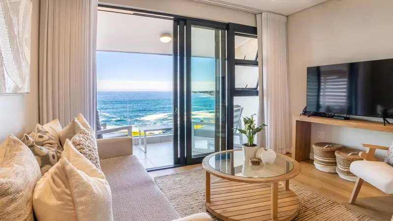 Un salon lumineux s'ouvre sur une vue mer par de grandes baies vitrées.