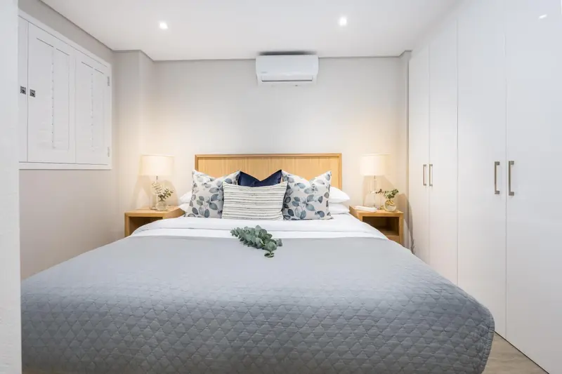 Une chambre lumineuse avec un grand lit et des rangements.