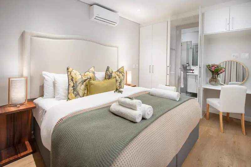 Une chambre lumineuse avec un grand lit recouvert d'une courtepointe verte et de coussins décoratifs.