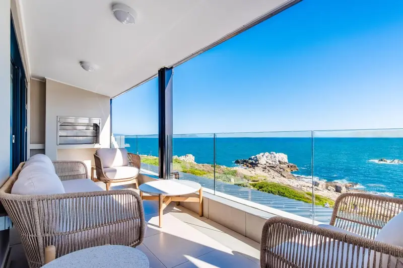 Terrasse aménagée avec mobilier en rotin donnant sur une vue mer dégagée.