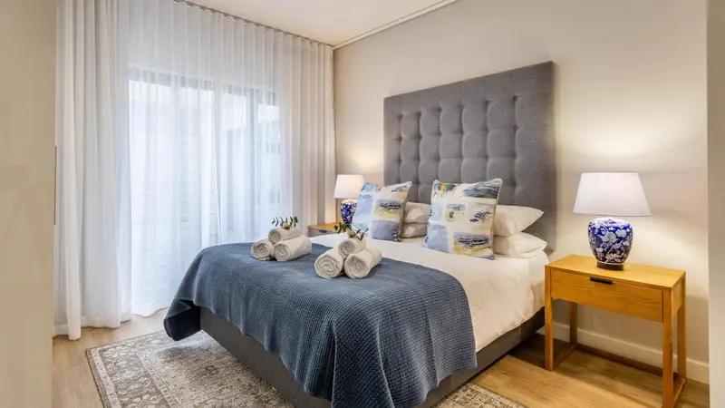 Une chambre lumineuse avec un grand lit et des oreillers décorés.