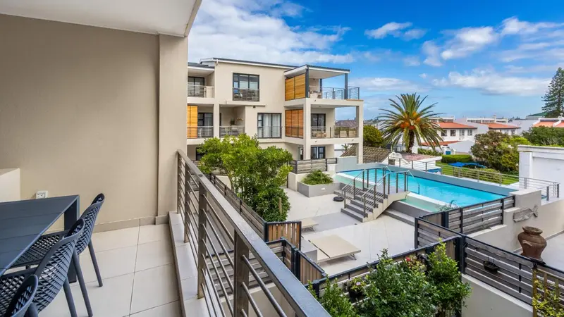 Vue aérienne sur une piscine et un jardin depuis un balcon.