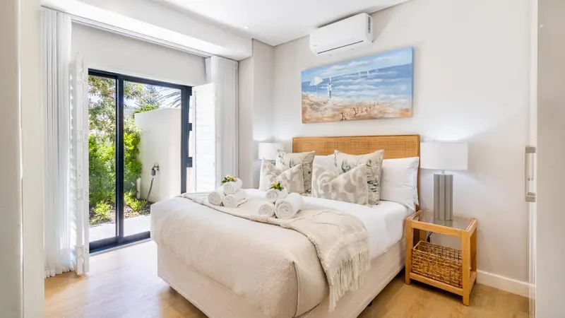 Une chambre lumineuse avec un grand lit et un accès à une terrasse.